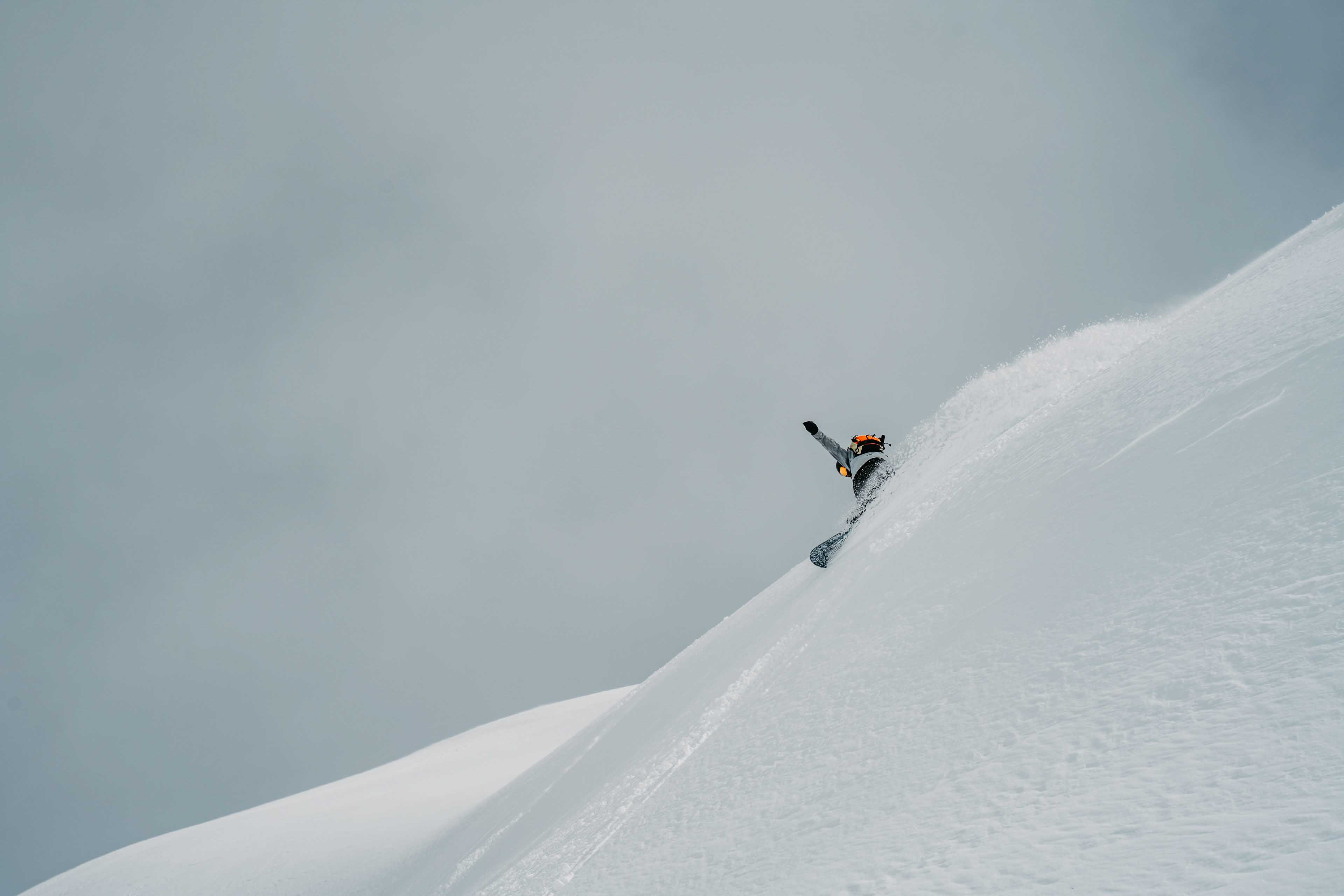 Snowboarder riding down the through fresh powder