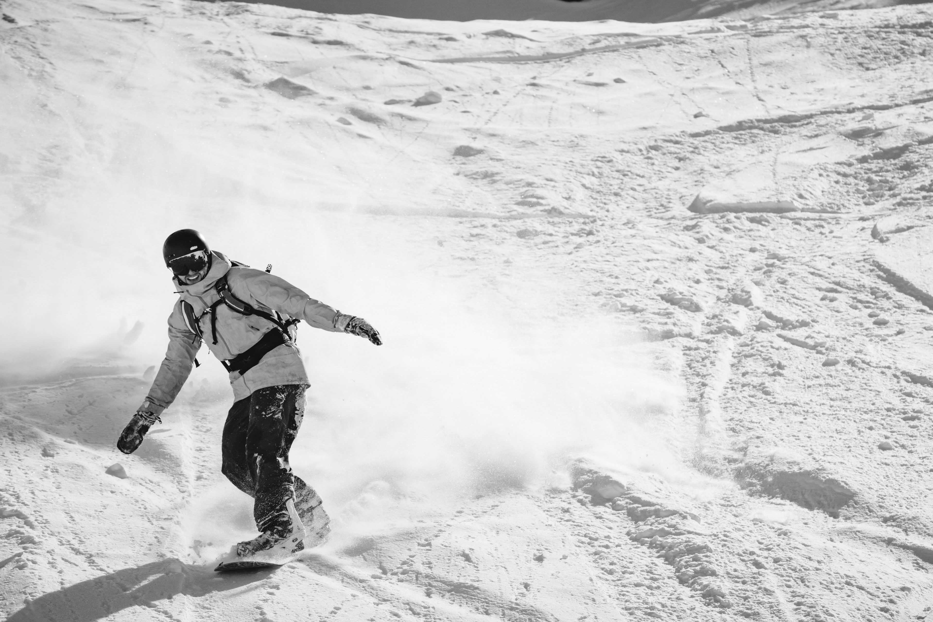 Snowboarder laughing while riding down the mountain