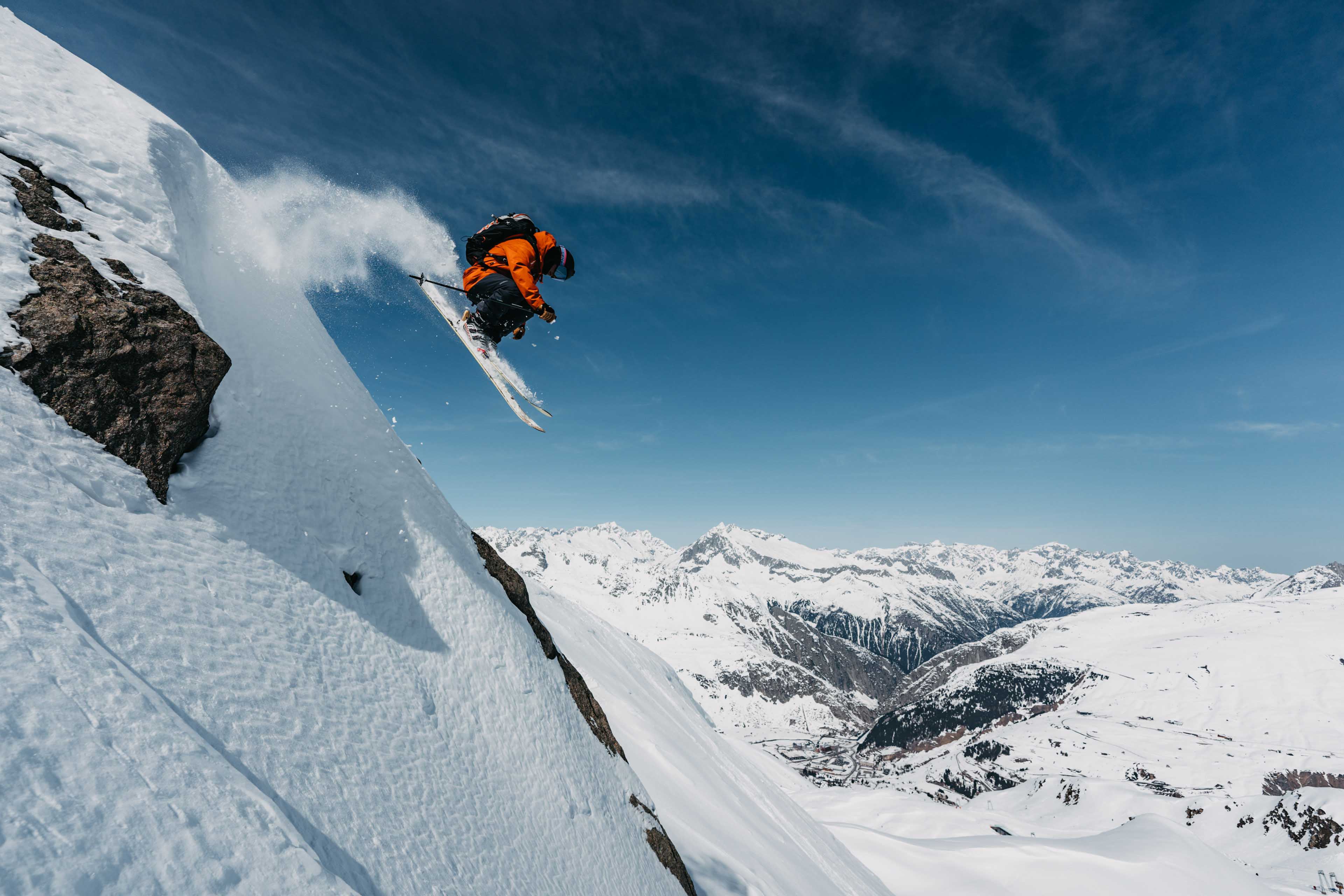 Skier jumping off a cliff, Andermatt in the background