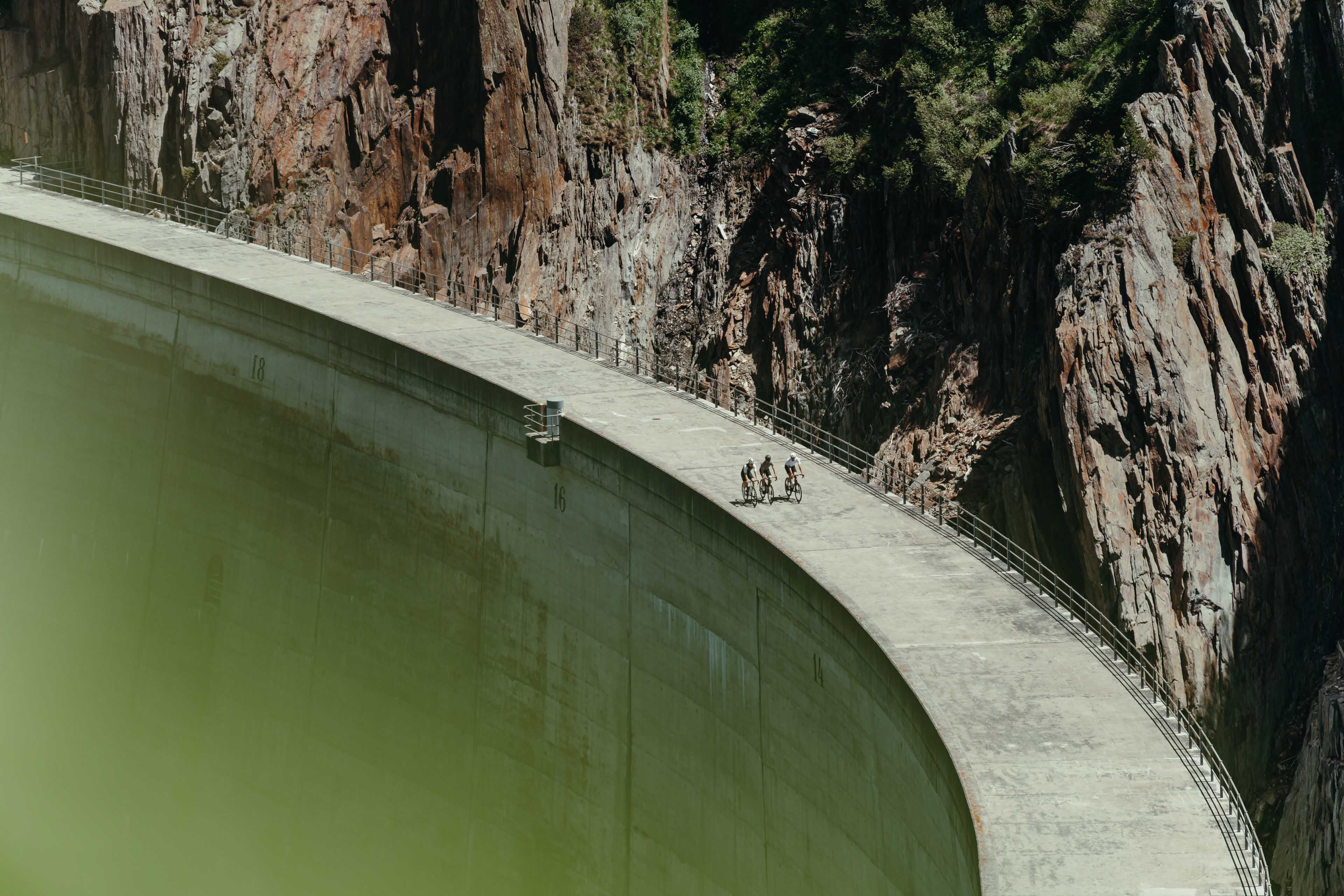 Group of cyclists in the alps on a reservoir dam