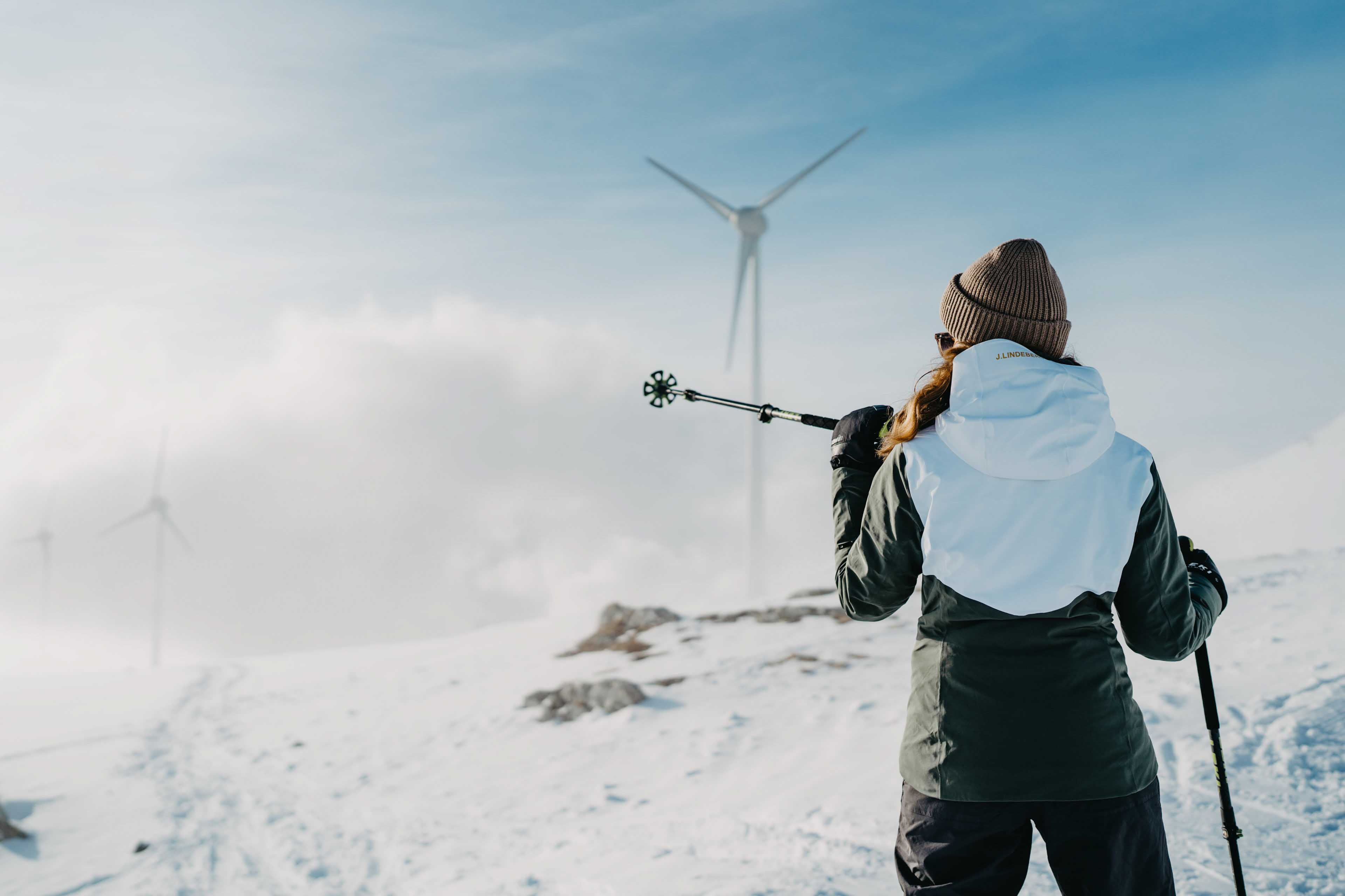 Women in the snow, a wind turbine in the background