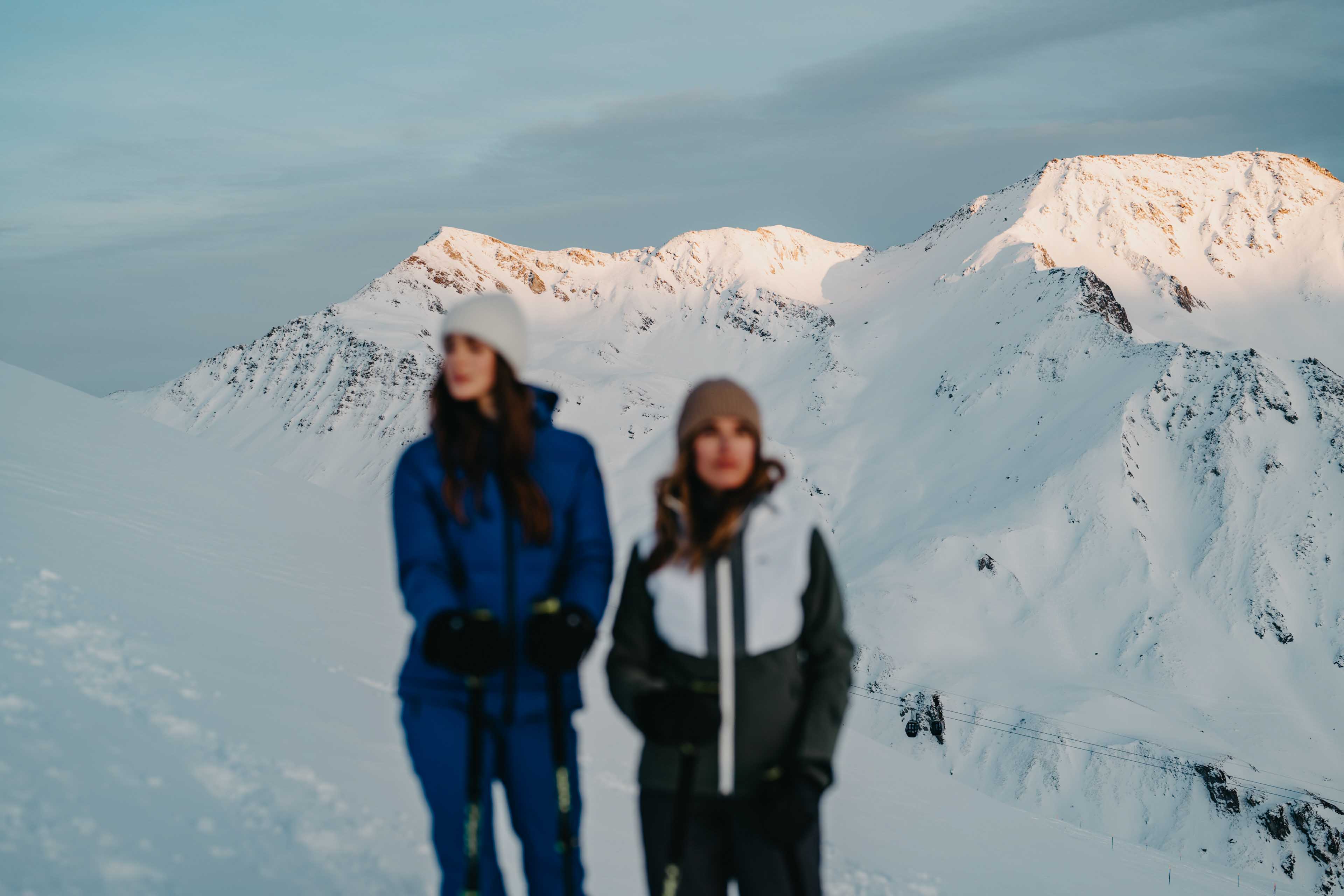 Sharp mountain summits in the background of two women